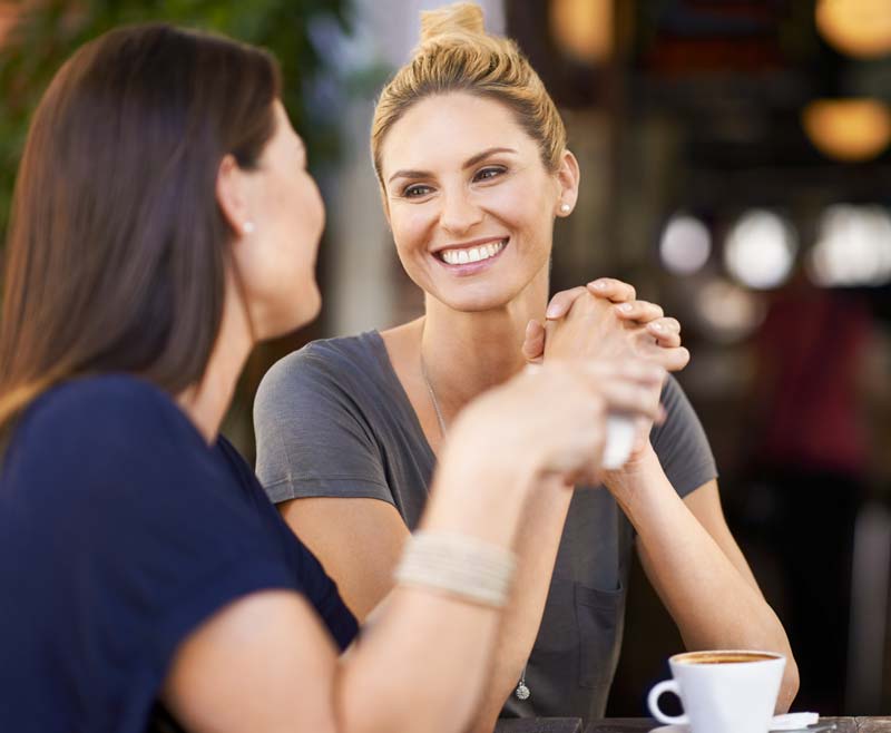 woman sitting with friend smiling confidently